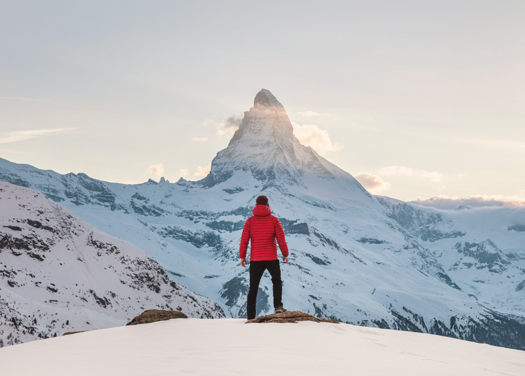 Person standing in front of snowy mountains.