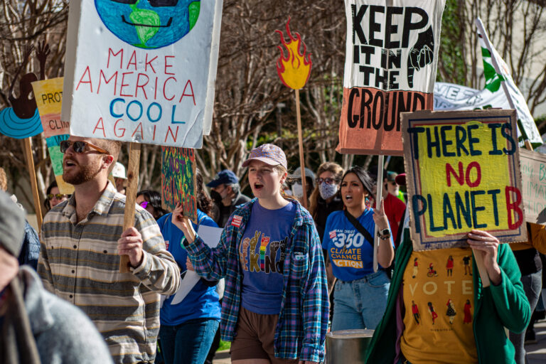 Group of people marching holding signs calling for climate action