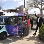 People in front of a microtransit vehicle.