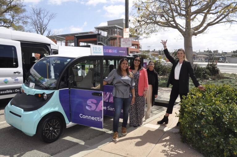 People in front of a microtransit vehicle.