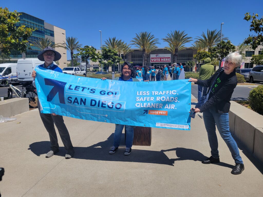 Three people holding up a sign