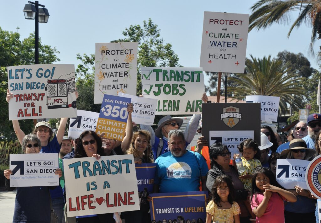 People holding up signs about getting better transit in San Diego.