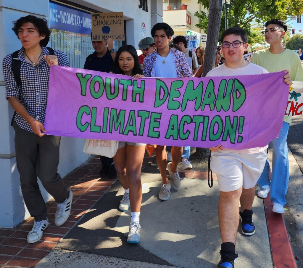 youth for climate members march with sign "youth demand climate action"