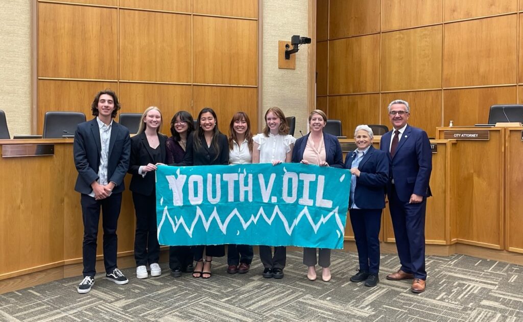 Youth and city council members in front of a sign that reads "Youth v. Oil"