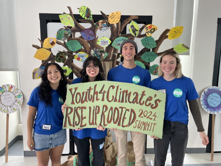 Students holding up a sign that reads Youth4Climate's Rise Up Rooted 2024 summit