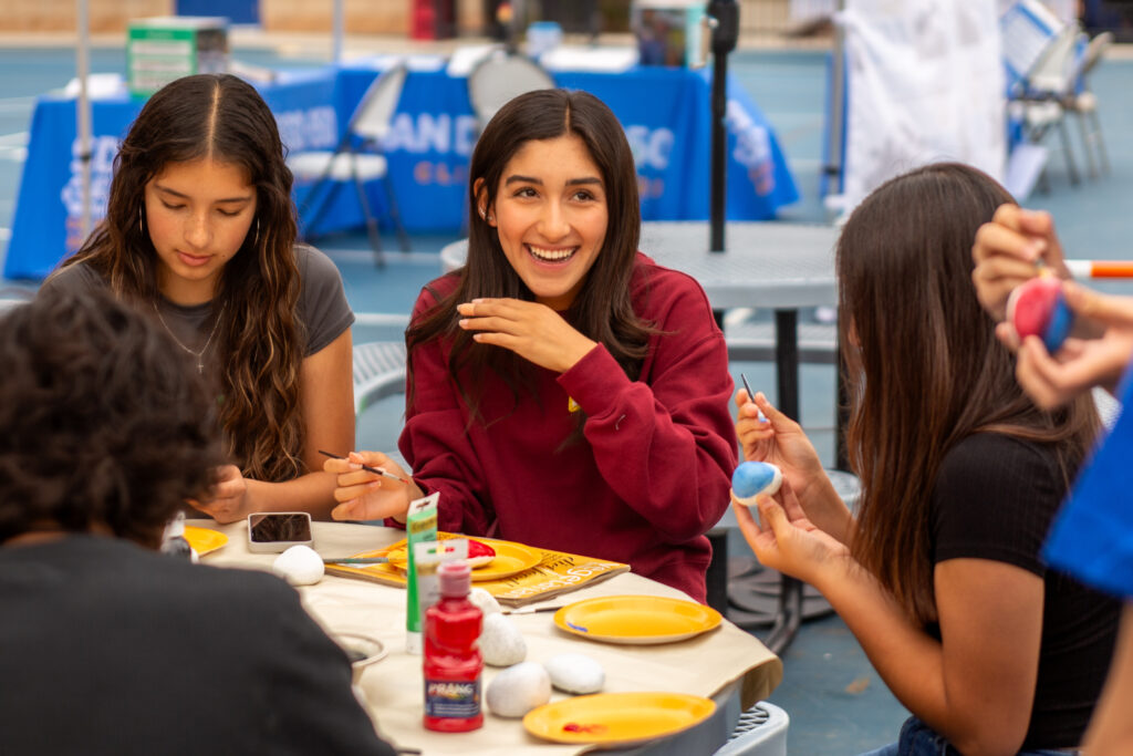 Youth students painting rocks and smiling