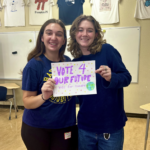 Two high school youth holding a sign that reads "Vote 4 Our Future".