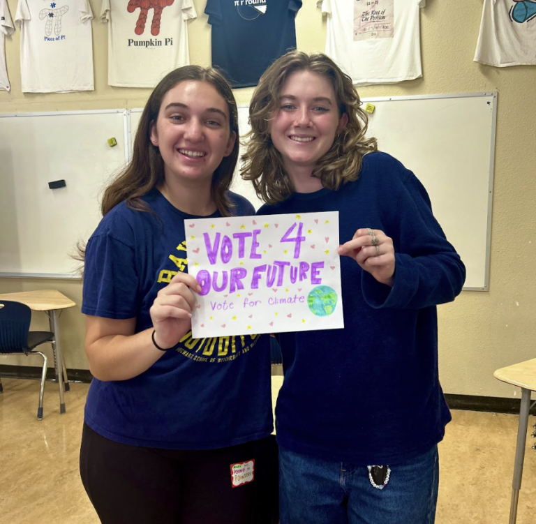 Two high school youth holding a sign that reads "Vote 4 Our Future".