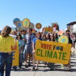 Youth rally, students holding a sign that says "Vote for Climate".