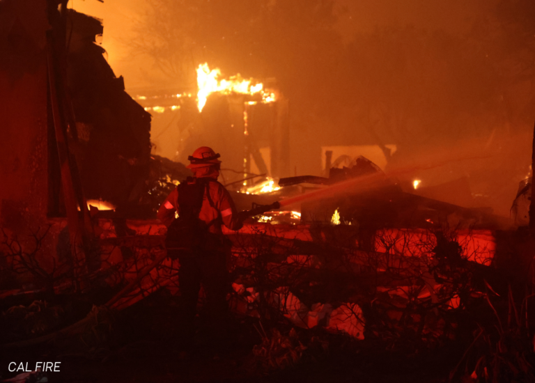 Firefighter spraying water over fire