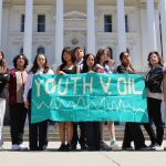 Youth members holding a "Youth v. Oil" sign in front of the capital building