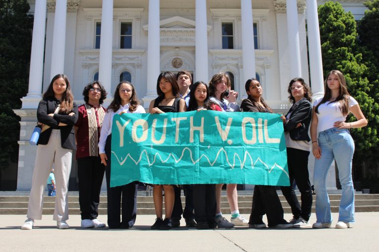 Youth members holding a "Youth v. Oil" sign in front of the capital building