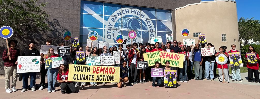large group of students holding signs that read "youth demand climate action"