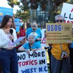 High school student speaking in front of people holding signs