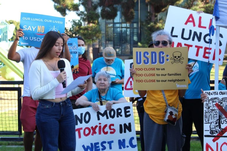 High school student speaking in front of people holding signs
