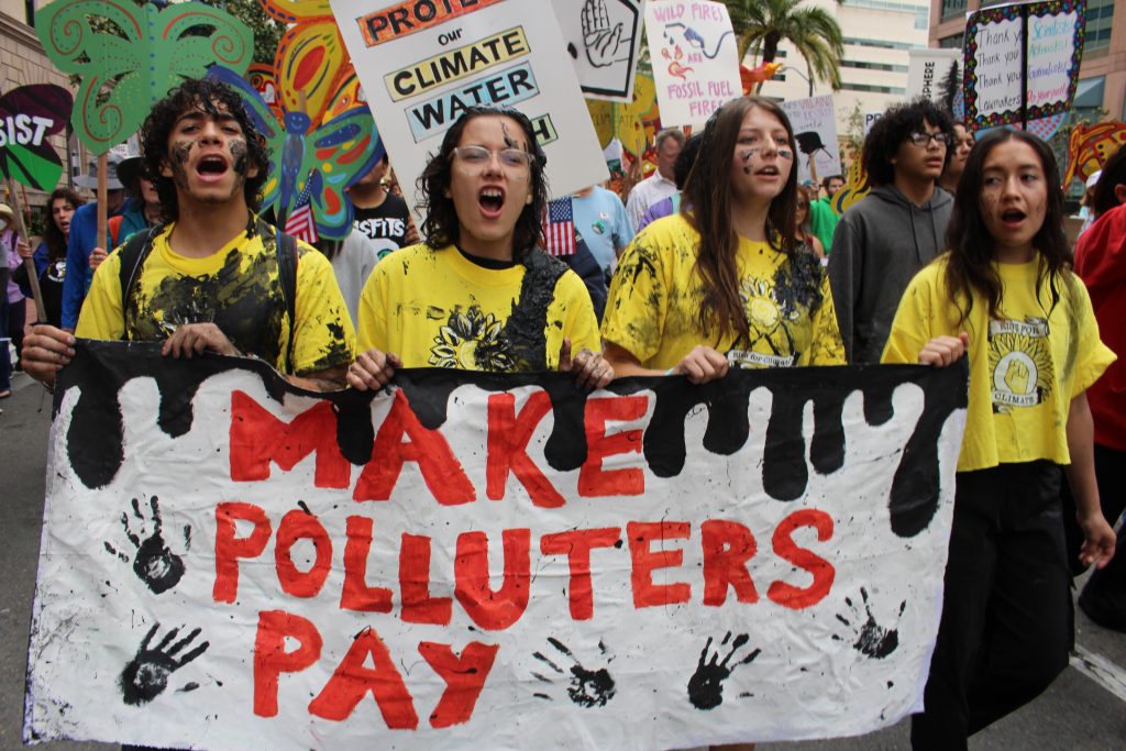 Four youth holding a "make polluters pay" sign