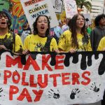 Four youth holding a "make polluters pay" sign