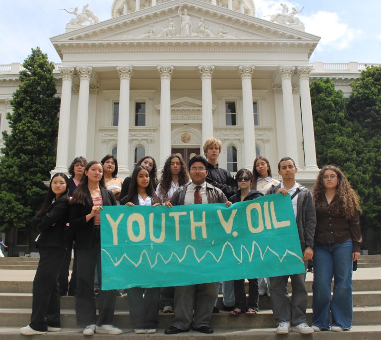 A group of youth standing in front of the CA state capital building holding a sign that reads " Youth v. Oil"