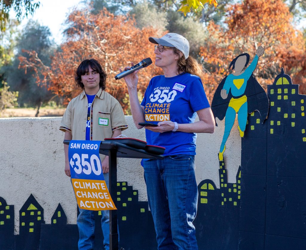 Masada speaking in front of a podium holding a microphone.